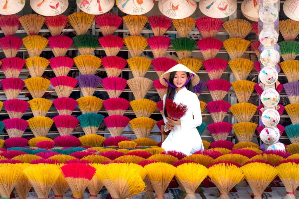 Asian woman crafting incense sticks in vibrant traditional setting, Vietnam.
