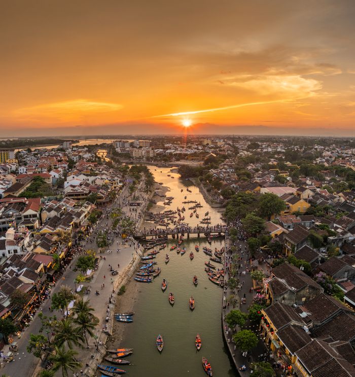 Stunning aerial view of Hội An with vibrant sunset and flowing river, showcasing the city's beauty.
