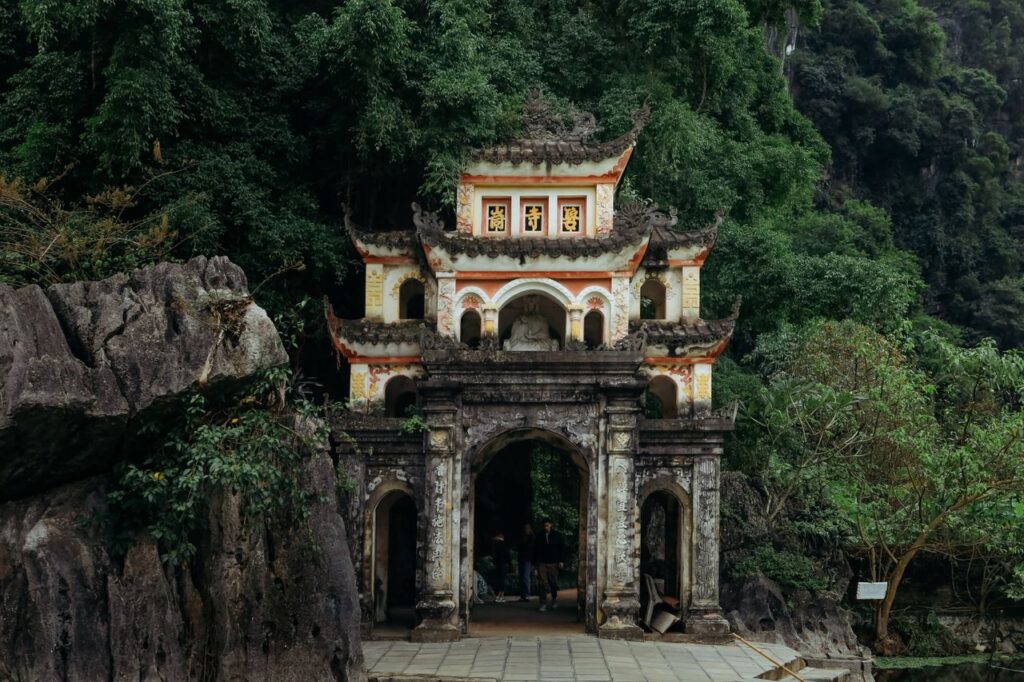 Historic temple gate amidst dense greenery in Ninh Bình, Vietnam, showcasing stunning architecture.