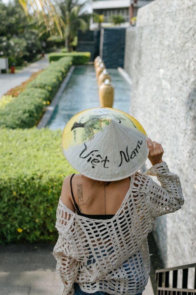 Back view of a woman wearing a Vietnamese hat walking down a garden path.