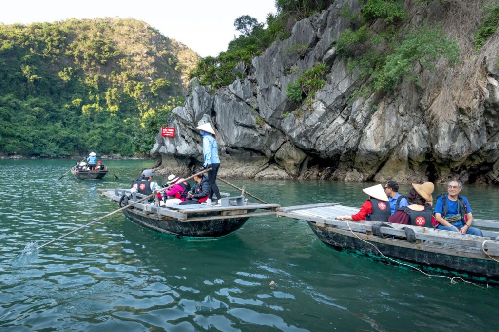 Tourists in traditional boats explore scenic Halong Bay cliffs.
